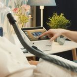 Caregiver adjusting settings on a Löwenstein prisma VENT 40 ventilator beside a patient using a mask at home